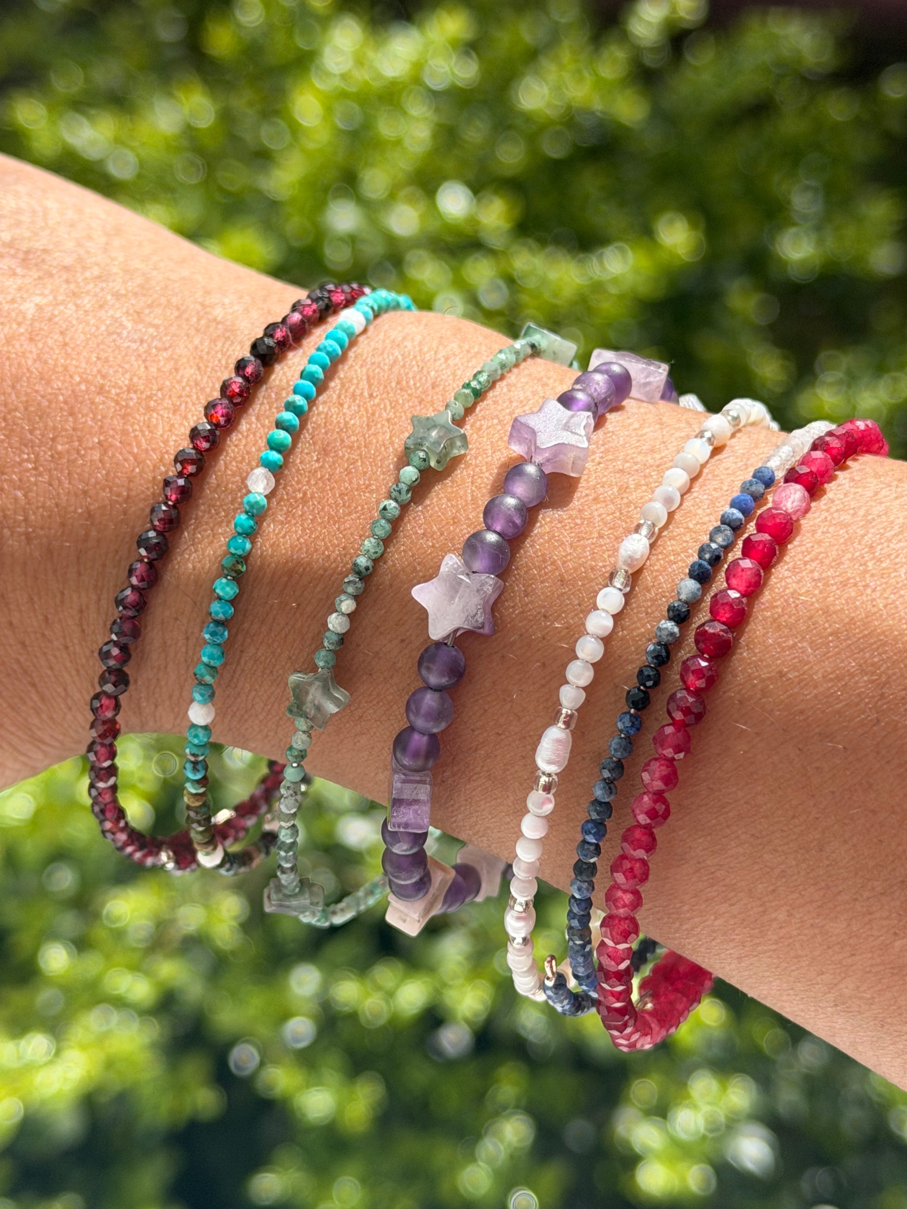 Two silver memory-wire bracelets with freshwater pearls, mother-of-pearl round beads, and small glass accent beads, shown side by side on a wrist.